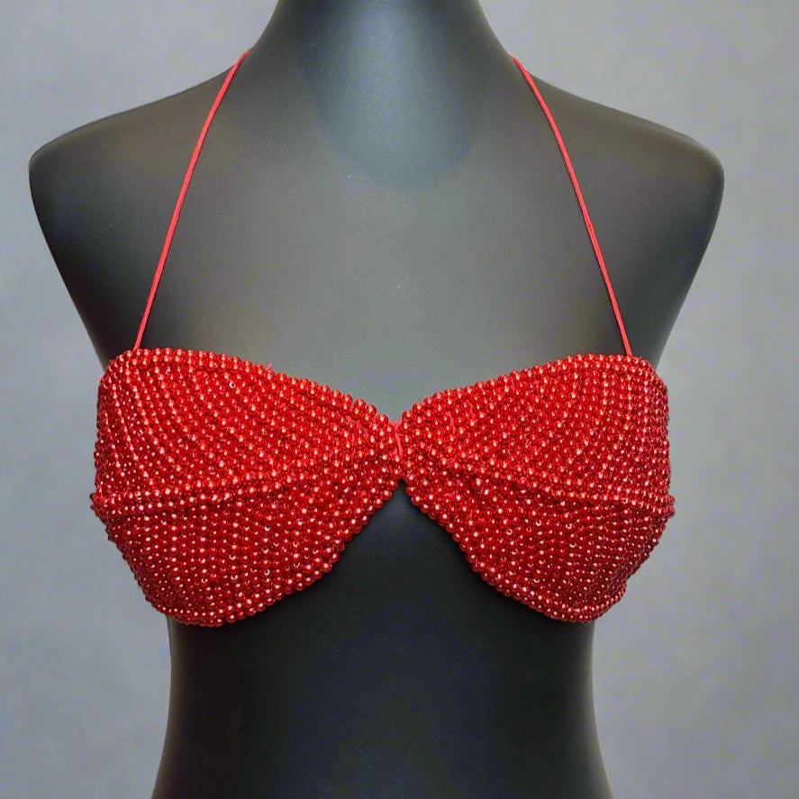 Red beaded bikini top on a black mannequin against a white background