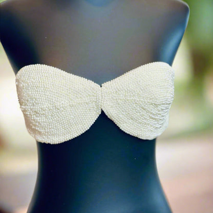 White beaded strapless top on a mannequin with a blurred background