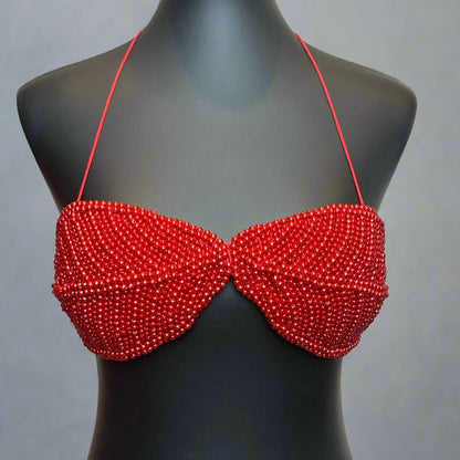 Red beaded bikini top on a black mannequin against a white background