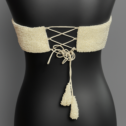 White beaded corset belt on a black mannequin against a gray background