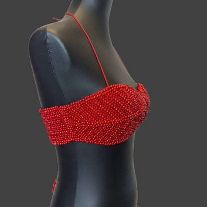 Red beaded top on a black mannequin against a white background