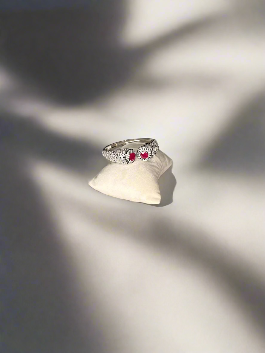 Silver bracelet  with red gemstones on a white cloth over a wooden surface