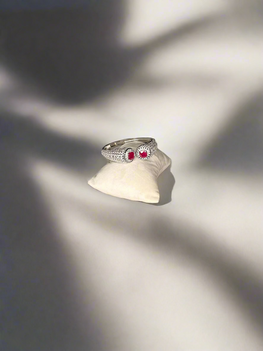 Silver bracelet  with red gemstones on a white cloth over a wooden surface