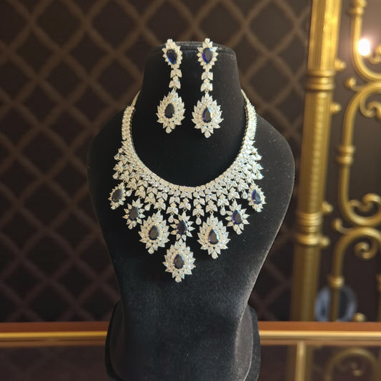 Jewelry set with necklace and earrings on a black mannequin bust against a decorative background.